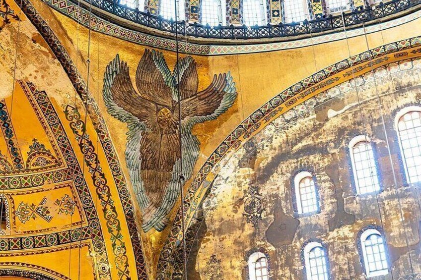 A mosaic of an eagle on a yellow background with intricate patterns and a damaged wall with arched windows. 2