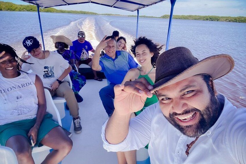 A group of people on a boat with a water body and greenery in the background. 5
