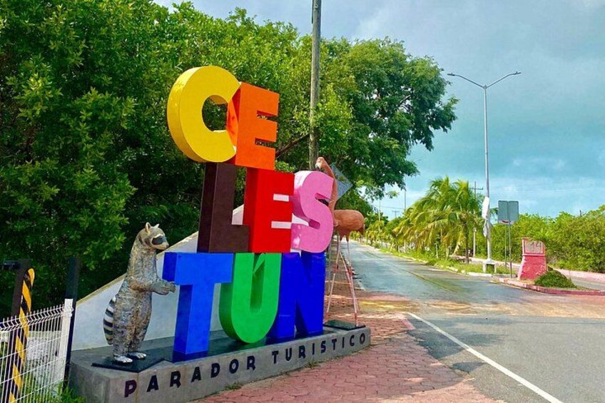 Une enseigne colorée avec les lettres « CELES » et « PARADOR TURISTICO », placée au bord d’une route bordée d’arbres, sous un ciel dégagé. 2