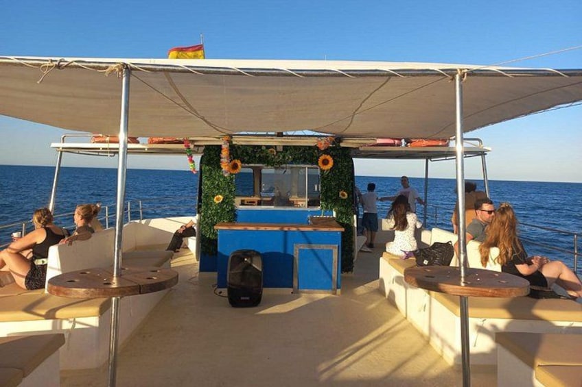 Een boot met een overdekte zithoek, een bar en mensen die ontspannen. 4