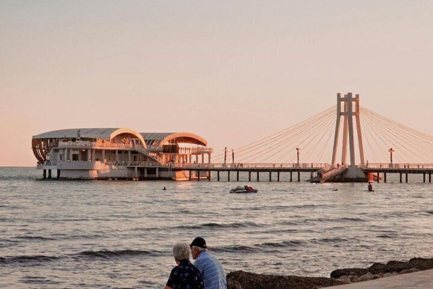 A waterfront with a bridge and a floating structure. 1