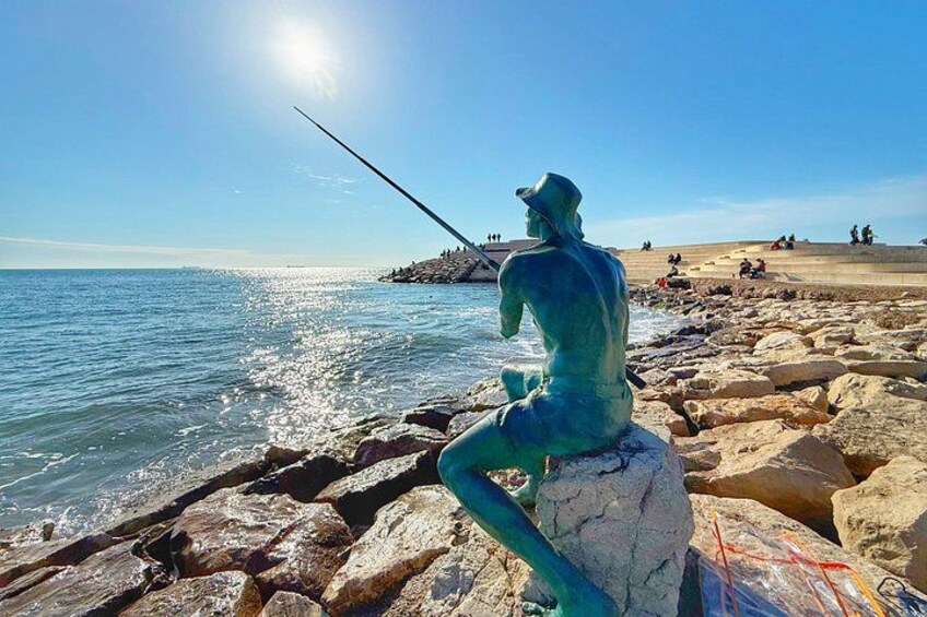 En statue af en person, der fisker ved havet. 5