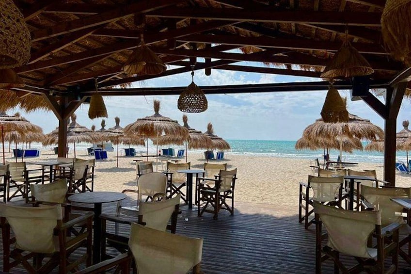 A beachside restaurant with thatched umbrellas and wooden tables. 3