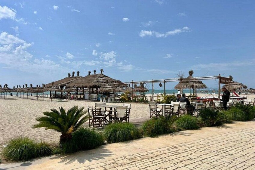 A beachside restaurant with outdoor seating, palm trees, and thatched-roof structures. 4