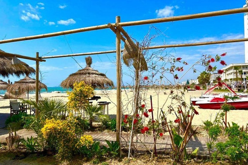 A beach with thatched umbrellas, a wooden fence, and a red boat in the background. 2