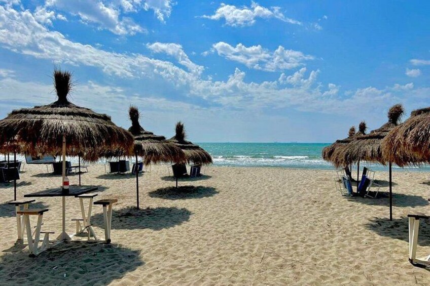 Una playa con sombrillas de paja y sillas de descanso. 2