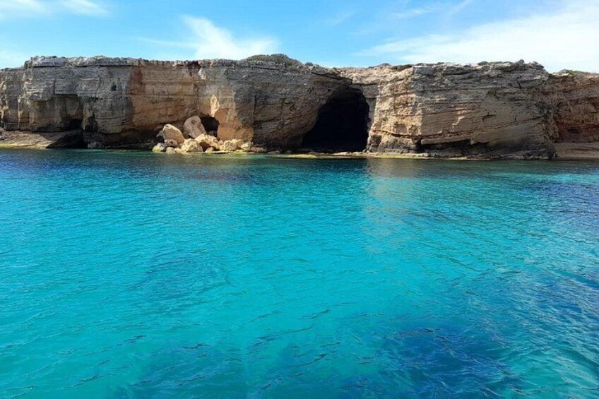 Une formation rocheuse côtière avec une entrée de grotte et une eau d’un bleu limpide. 2