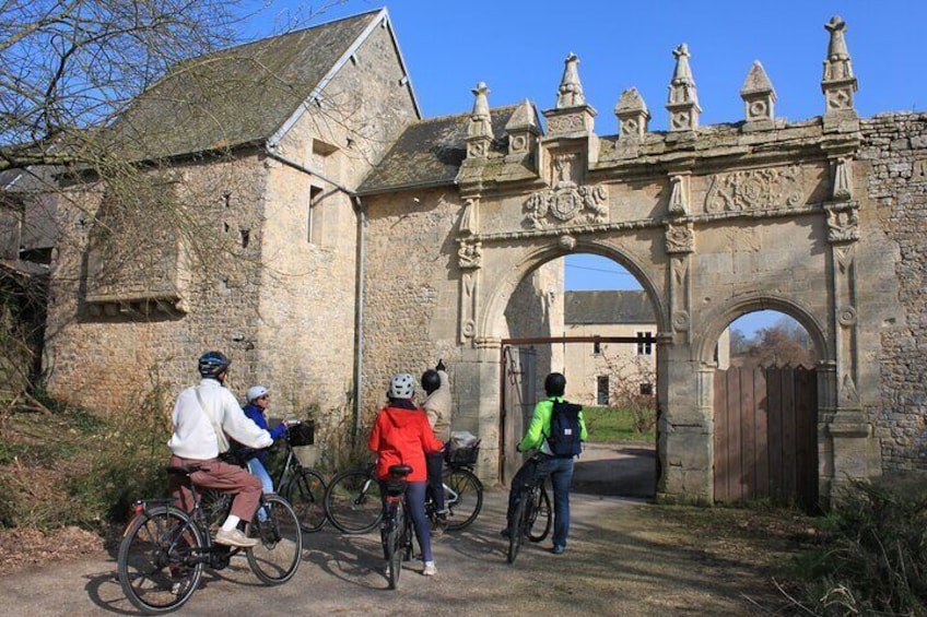 Cyclists approaching a historic stone archway. 1