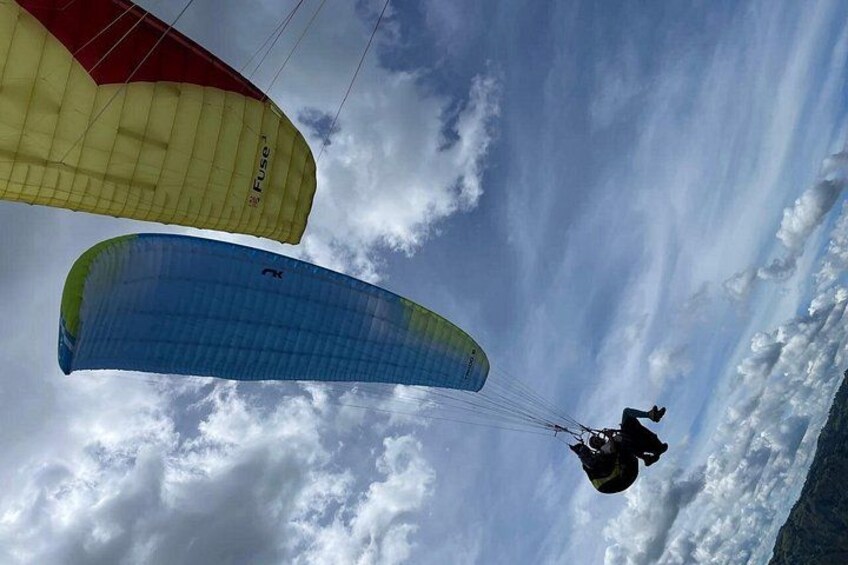 A paraglider with a blue canopy and a red canopy in the background. 1