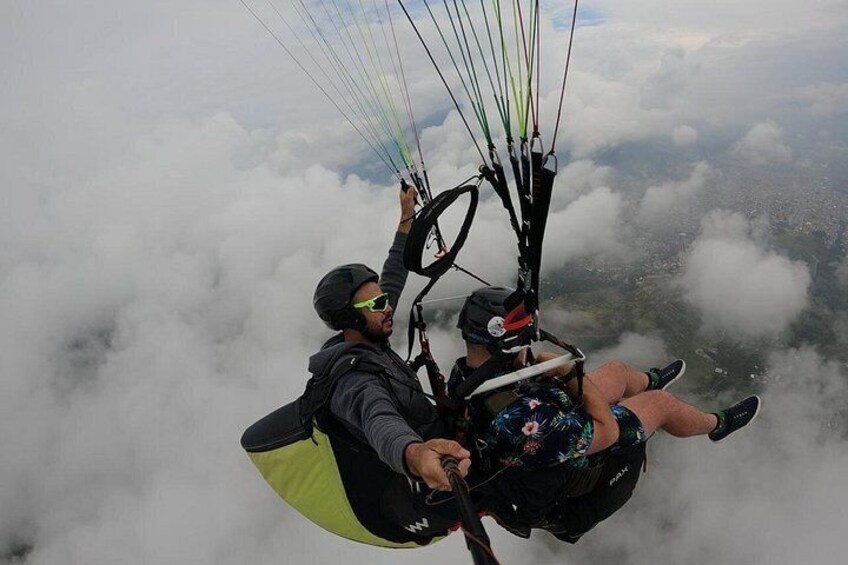 A person paragliding above clouds with a parachute harness and a helmet. 3
