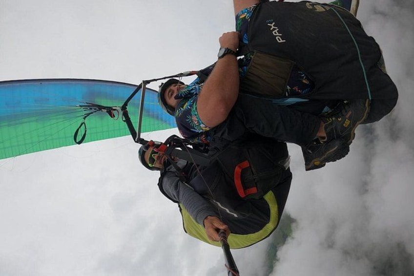 A person paragliding with a parachute, wearing a helmet and harness, and carrying a backpack. 3
