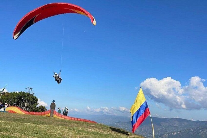 A paraglider in the air, a flag, and a mountainous landscape. 5