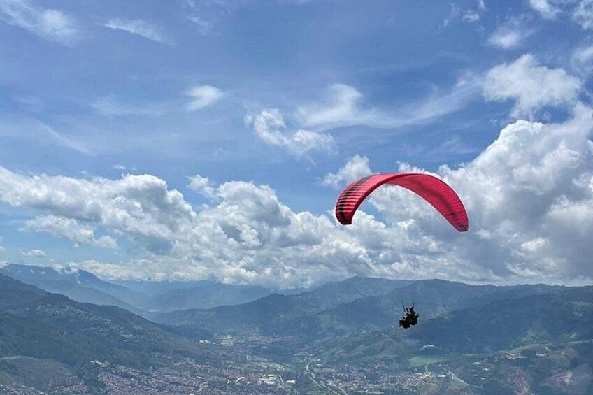 A paraglider with a red parachute flying over a mountainous landscape. 2