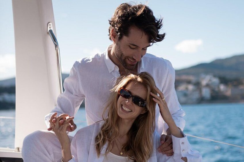Una pareja en un velero con un paisaje costero de fondo. 3