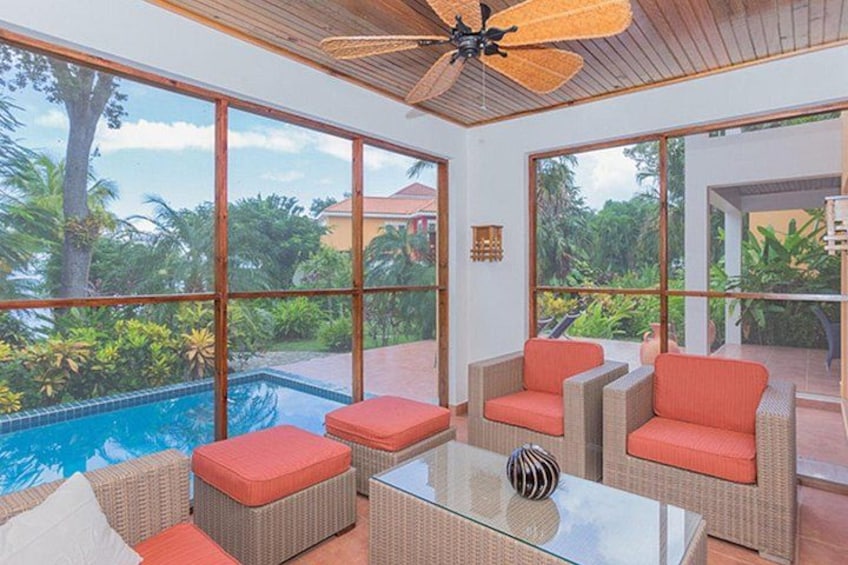 A poolside area with wicker furniture and a ceiling fan. 4