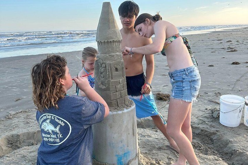 Un grupo de personas construyendo un castillo de arena en la playa. 5