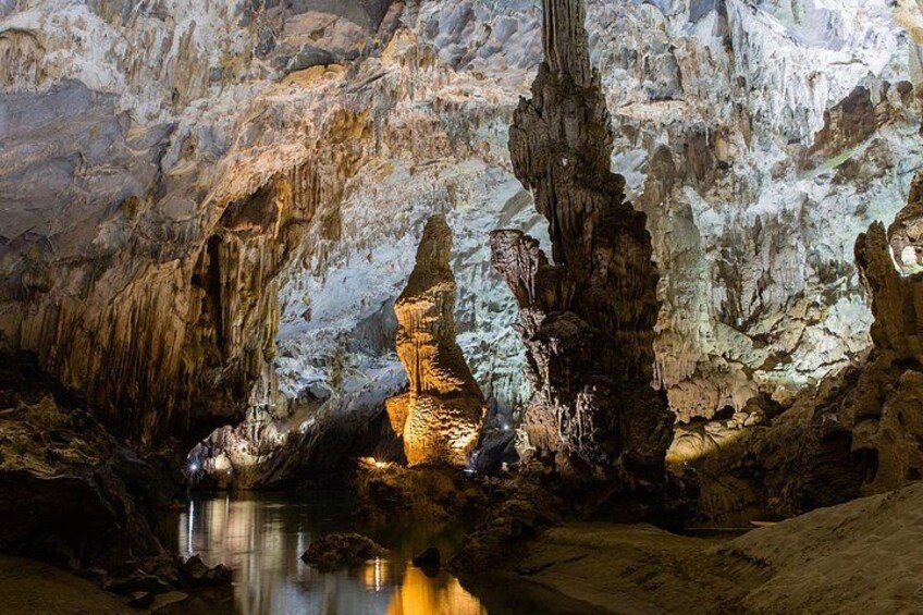 A cave with stalactites and stalagmites, a water pool, and a rocky landscape. 3