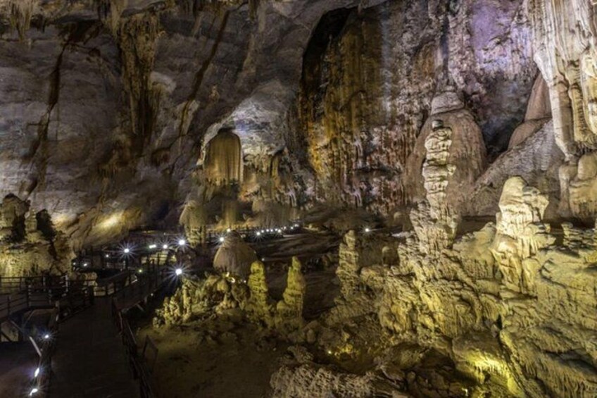 A cave with illuminated rock formations and a pathway. 4
