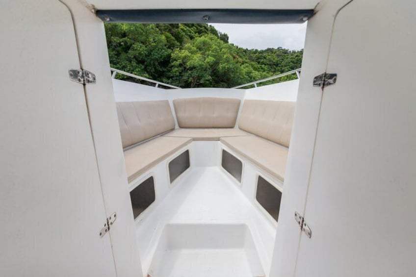 A boat interior with beige seating and a view of a forested landscape. 4