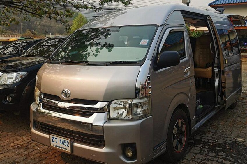 A silver Toyota van parked on a cobblestone surface with a license plate visible. 3