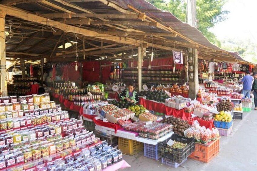 An outdoor market with various stalls selling fruits, vegetables, and packaged goods. 5