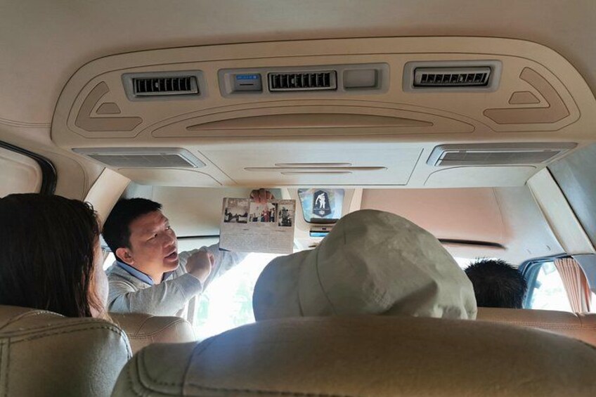 The interior of a car with a man holding a map, a woman seated in the front passenger seat, and a child in the back. 2