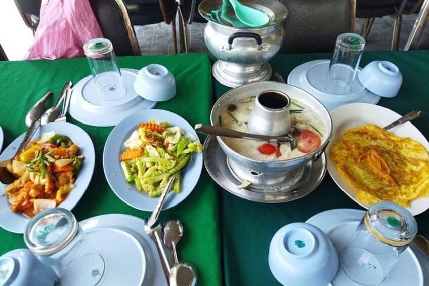 A table set with various dishes, including a hot pot, vegetables, and a fried egg. 4