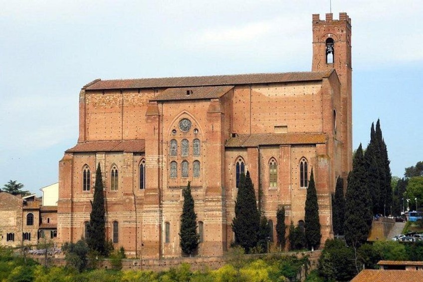 Un grand bâtiment en briques, doté d’une tour horlogée, de fenêtres en arc de cercle et d’une cloche. 3