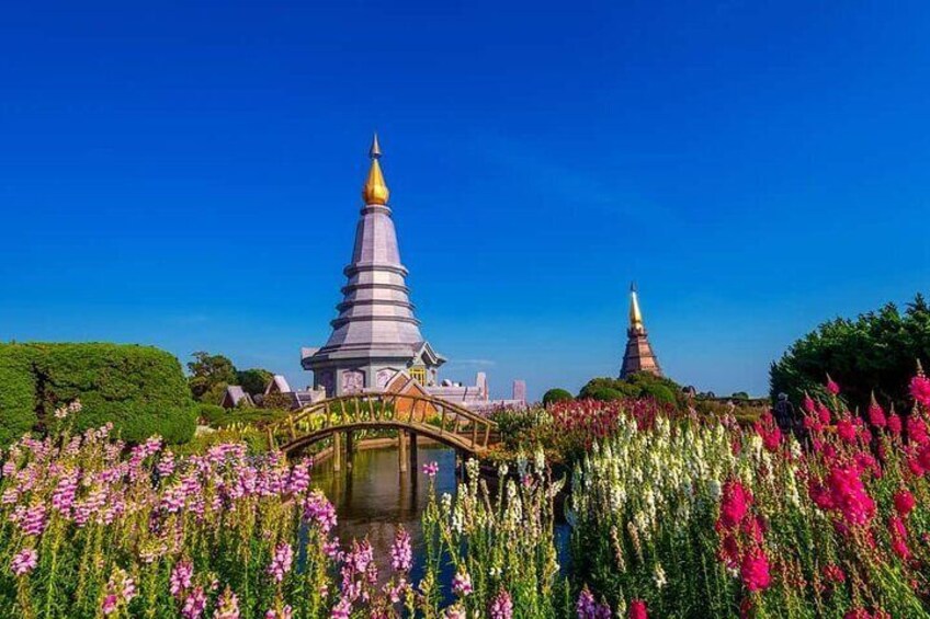 A temple with a golden spire, surrounded by vibrant flowers and a bridge. 5