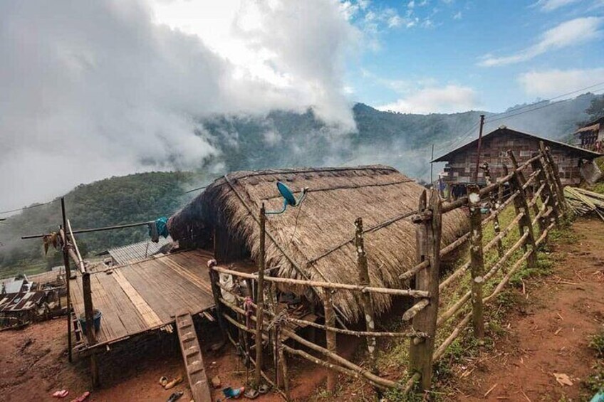 A thatched-roof structure with a wooden platform and a fence. 4