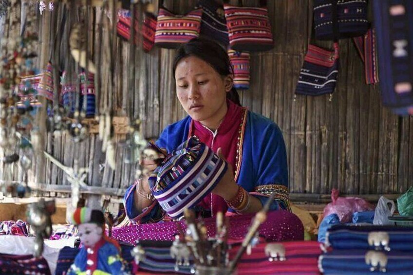 A person displaying colorful woven bags at a market stall. 2