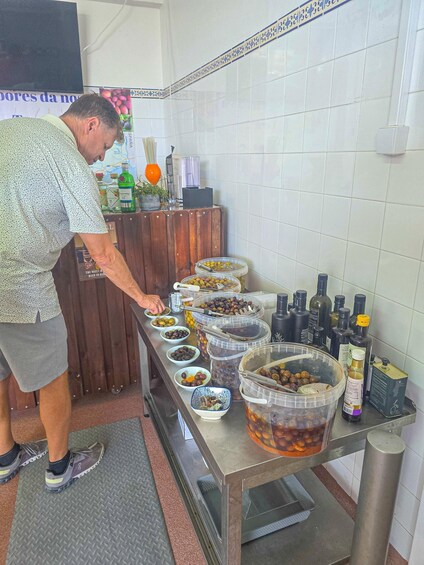 A person serving food from large containers on a stainless steel counter in a kitchen. 5
