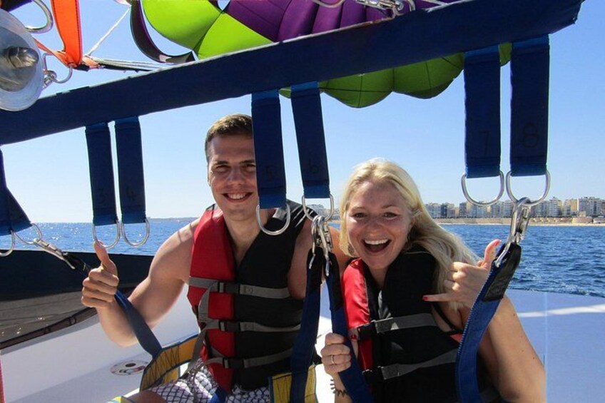 Two people on a boat, wearing life jackets, with a city skyline in the background. 3