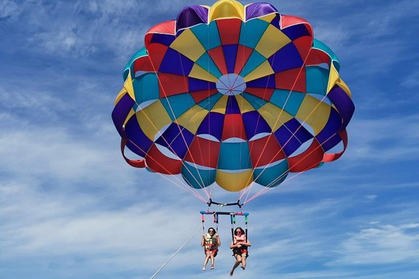 A parachute with a colorful pattern, a clear sky, and a person in a harness. 4