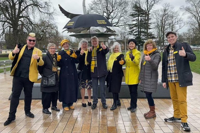 A group of people posing for a photo in a park with a monument in the background. 3