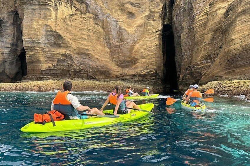 People kayaking in a canyon with clear water and rocky cliffs. 2