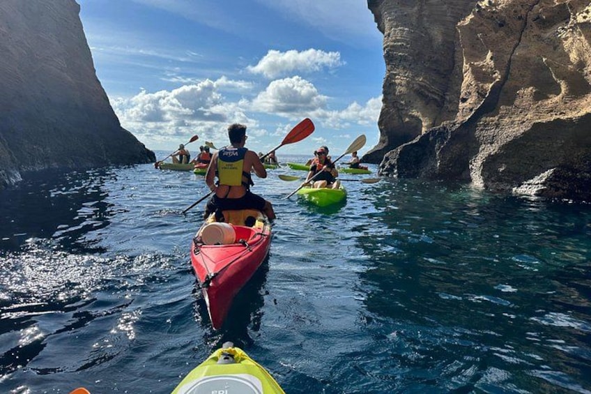 A group of kayakers navigating a narrow waterway between rocky cliffs. 4