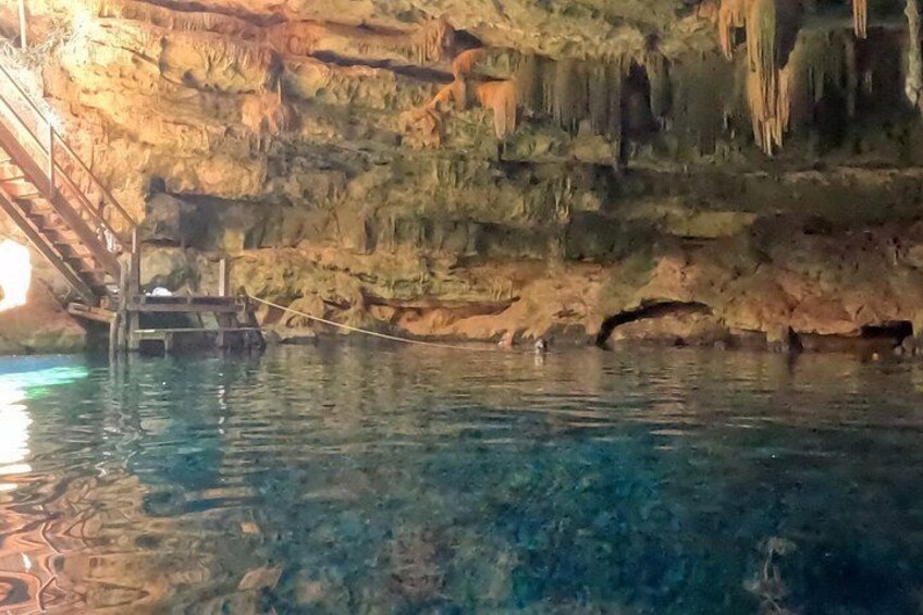 Une grotte avec de l’eau claire, des stalactites et un escalier en bois. 2
