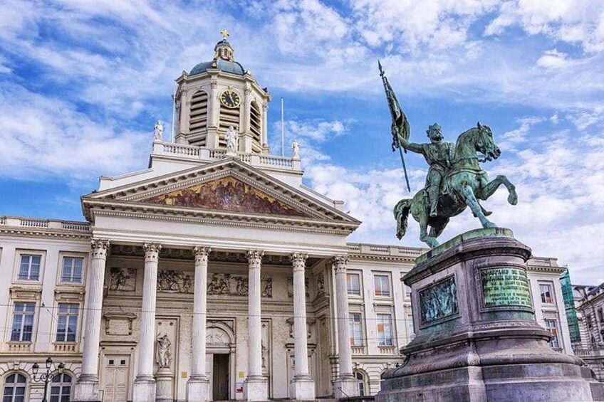 A neoclassical building with columns, a statue of a man on horseback, and a clock tower. 5