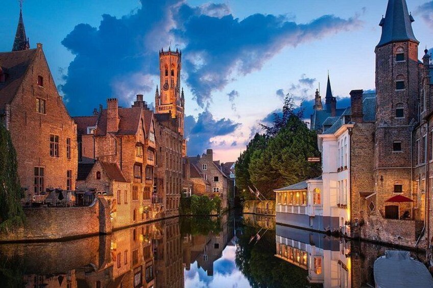 A historic European town with a canal, traditional architecture, and a prominent tower. 4