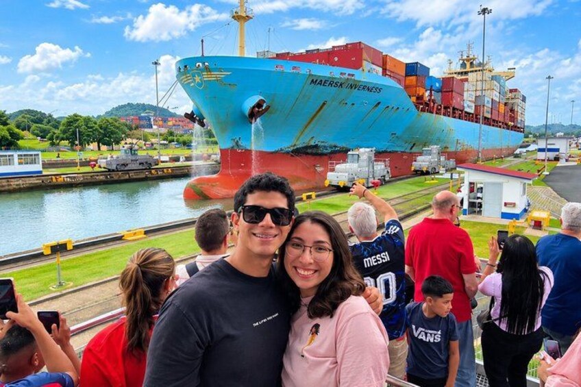 A large ship docked at a port with people taking photos. 1