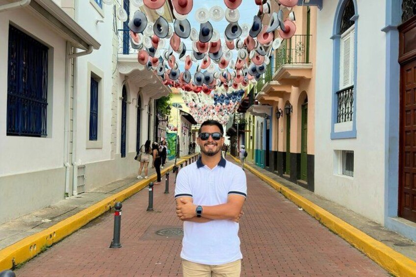 A street with a row of buildings, a pedestrian, and a decorative ceiling with circular patterns. 3
