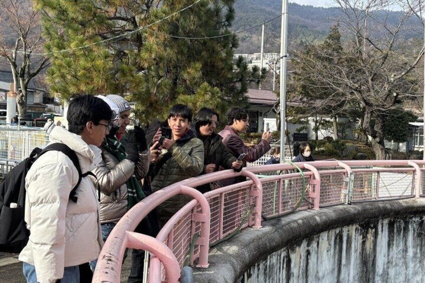 Des personnes se tiennent sur un pont, avec une cascade en contrebas. 1