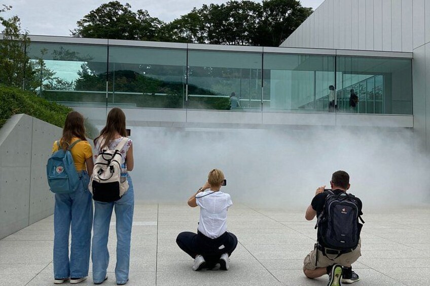 A group of people standing and squatting in front of a modern building with glass windows. 5