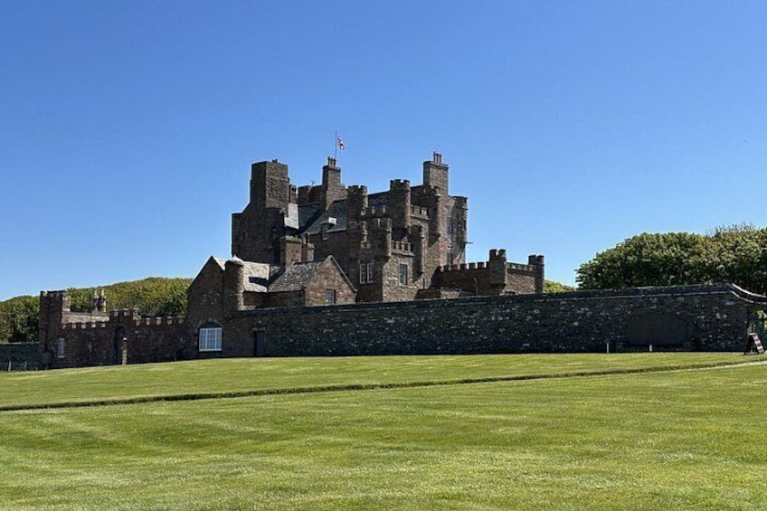 A historic castle with a large lawn in front. 2