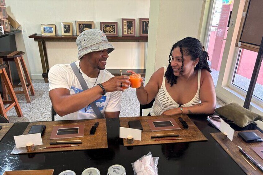 Dos personas sentadas en una mesa con bebidas, rodeadas de cuadros enmarcados y muebles de madera. 3