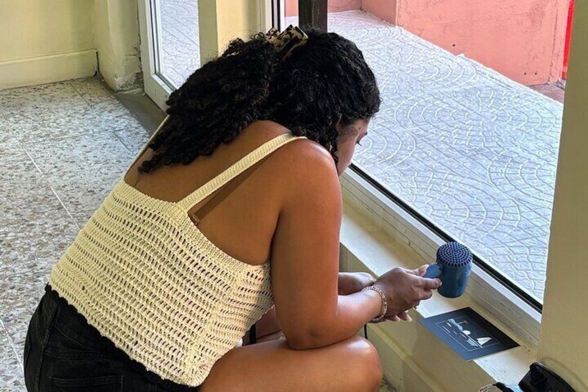 Una persona sentada junto a una ventana, sosteniendo un objeto azul. 2
