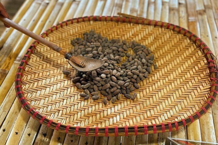 A woven basket filled with coffee beans on a bamboo mat. 4