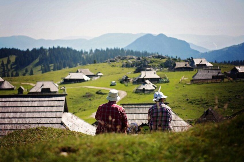 Two people overlooking a village with traditional houses and mountains in the background. 4