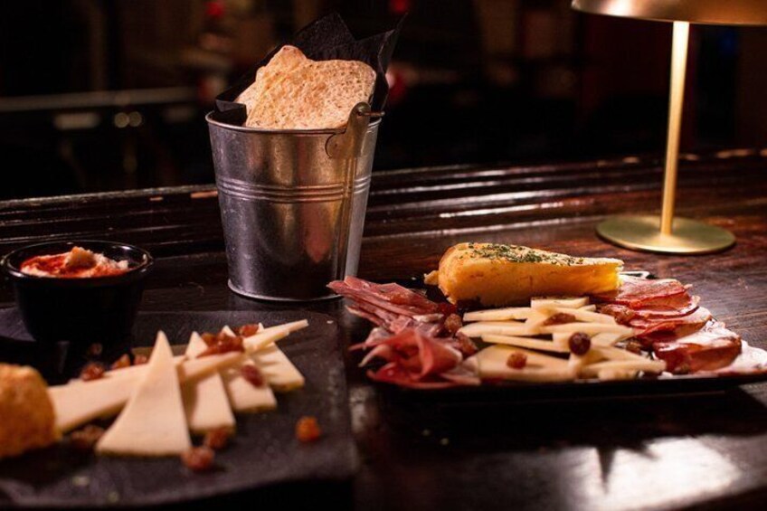 A charcuterie board with various cheeses, meats, and a baguette on a wooden table. 5